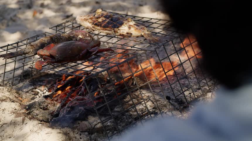 A person walking next to a fire cooking food