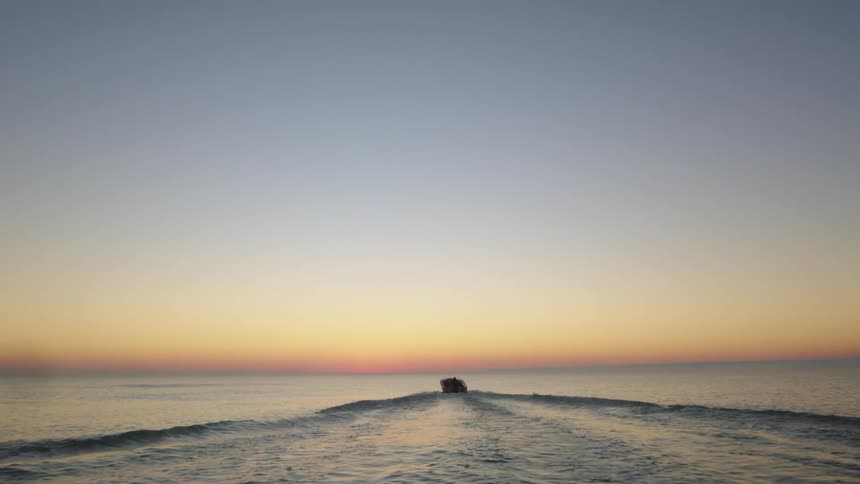 A boat in the ocean with waves with the sky and clouds in the background