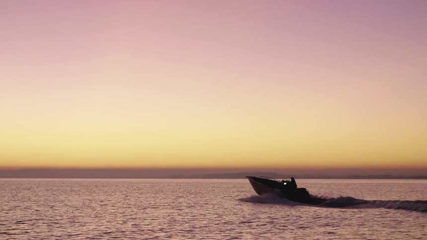 A boat travels across a bay at sunrise