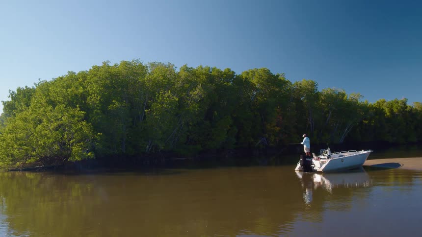 Man tries to catch fish with a fishing line in a boat on the river