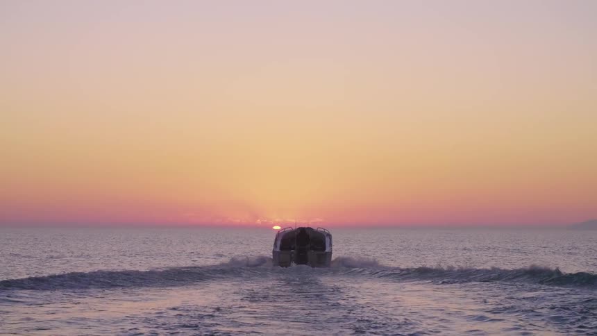 A person sails on their boat as the sun rises