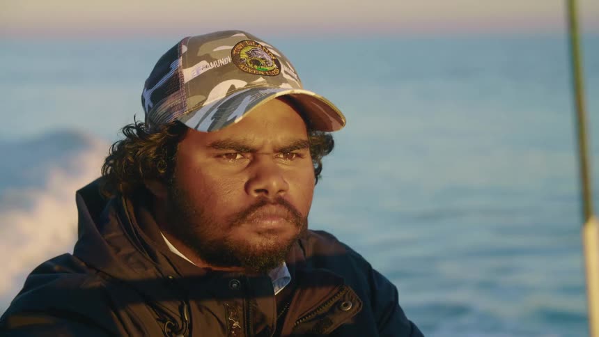 A man in a camouflage hats sails a speedboat through the ocean