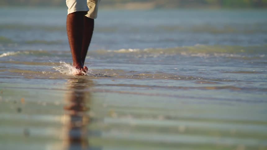 Man walks barefoot in water on beach