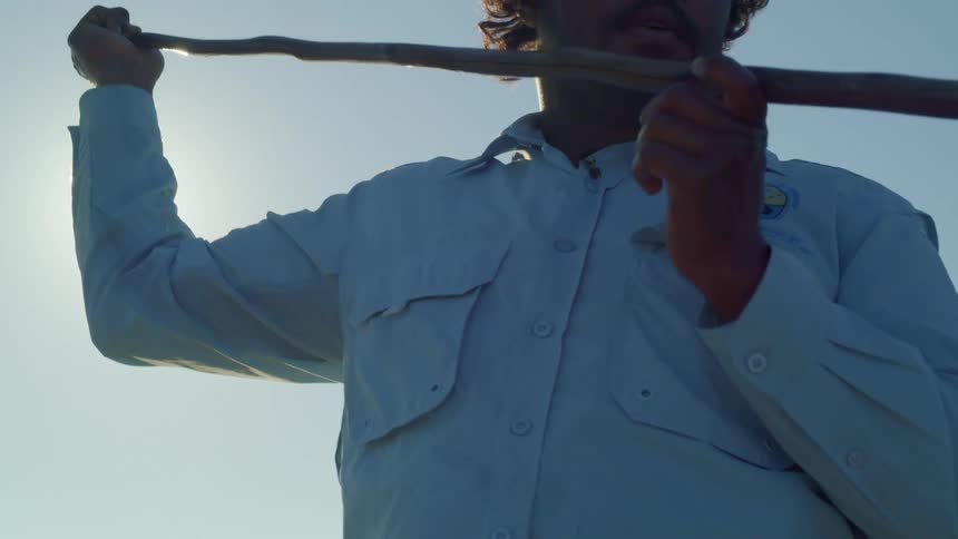 Man messing around with a stick focusing on something