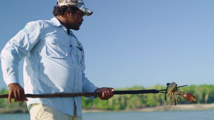 A man fishing for crab with a stick