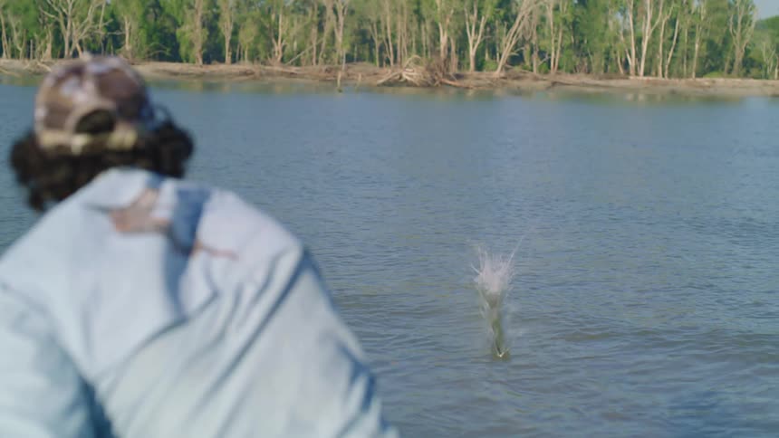 A fisherman throws a spear into a lake