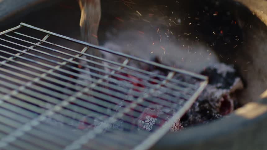 A person poking coals with a stick in a bowl