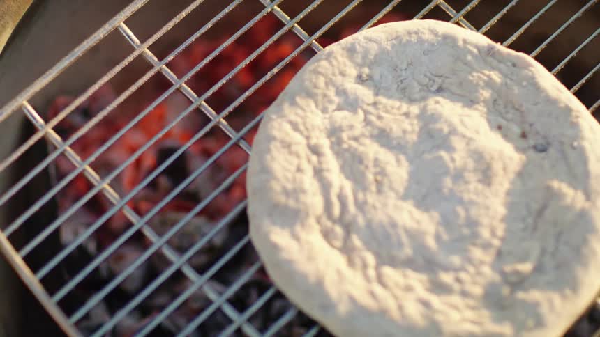 Damper lies on a grill above glowing hot charcoal