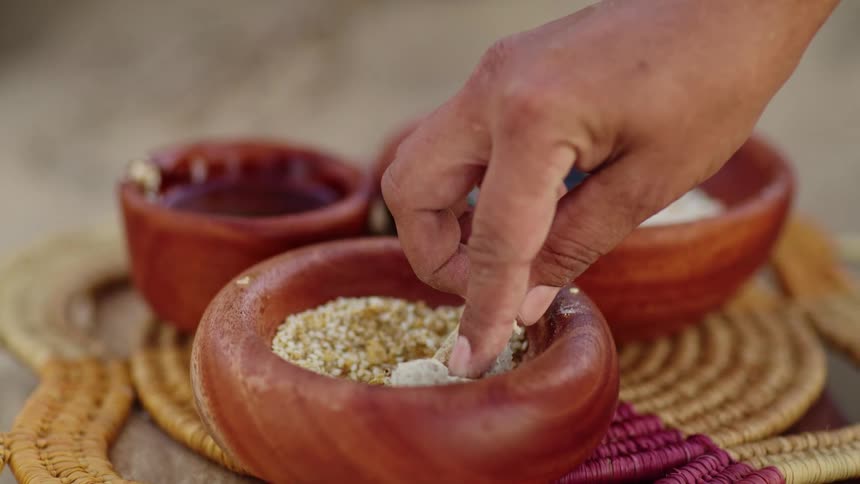 A person dips damper in seeds to eat