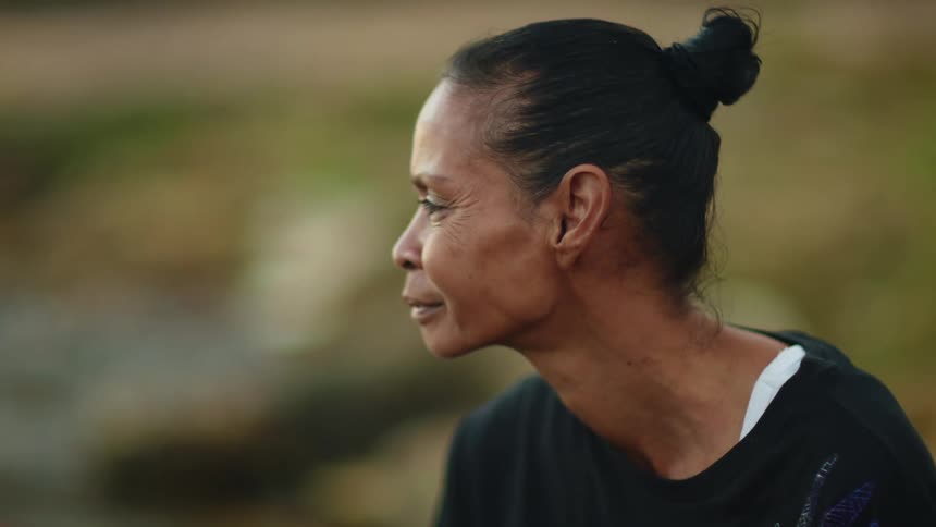 Older black woman sitting outside looking away from camera