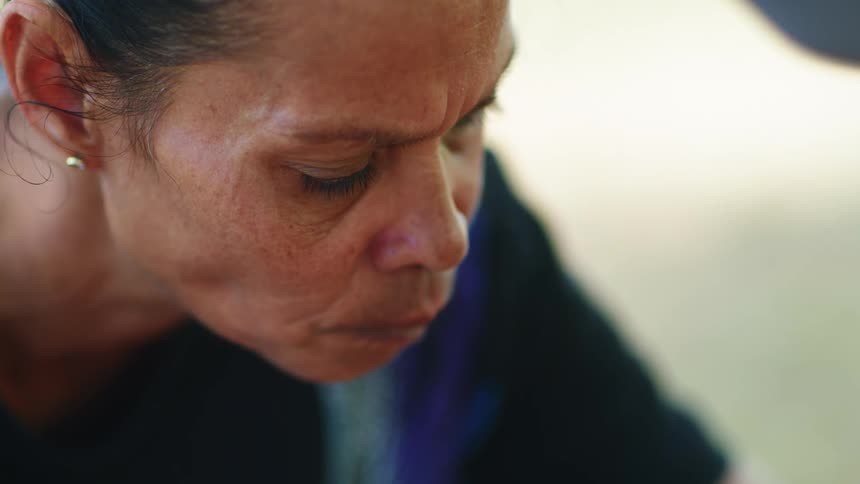 A woman chews with her mouth closed as she sits outdoors
