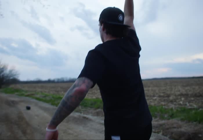 Man does lunges down gravel driveway holding weight above head