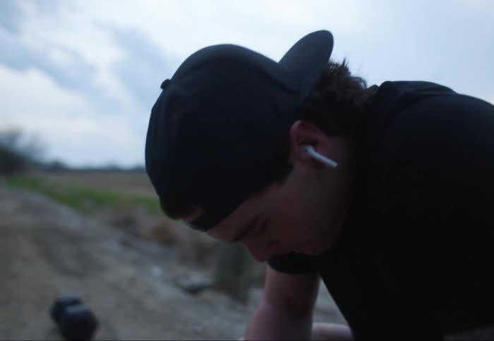 A man is outdoors wearing a hat and listening to music