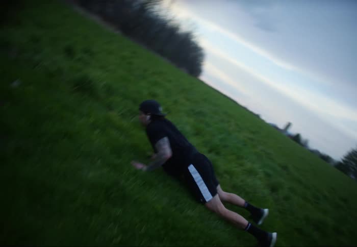 A man alternates between pushups and jumping jacks as he exercises in a field during the day