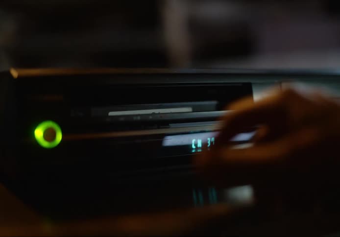 A person inserts a video cassette into a vhs player