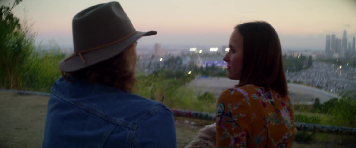 Young couple with dog sit on scenic overlook above large city