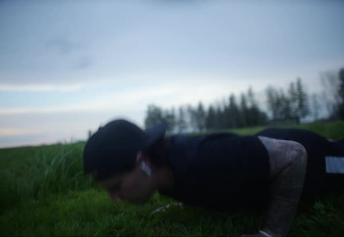 A person does push ups in the middle of a rural grass field