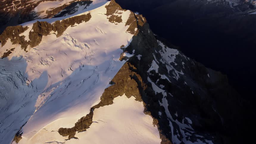 Aerial view of snow covered mountains at dusk is displayed