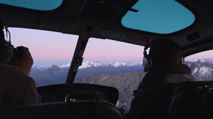 A helicopter passenger takes photographs as the aircraft hovers over a mountain range