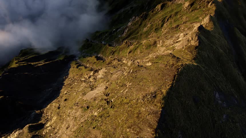 An aerial view of a mountain range and clouds on a winter day