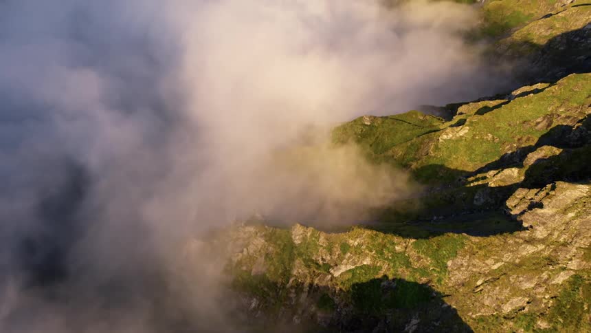 A mountain range with its summit covered in greenery and its valley shrouded in thick fog