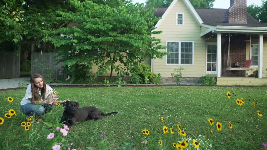 A woman is petting her dog in the yard