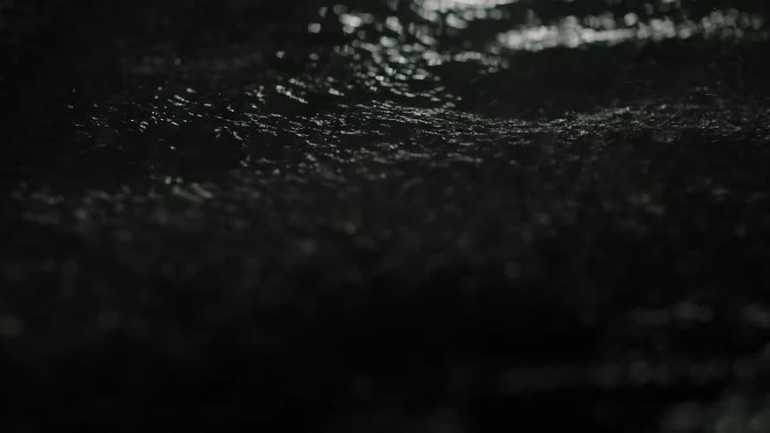Rain falls into a puddle on the ground during a storm