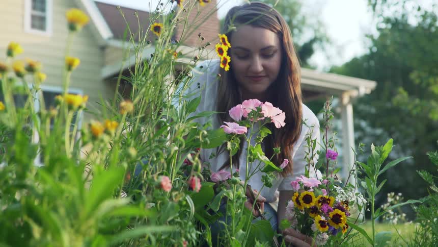 A woman sniff flowers from a home garden