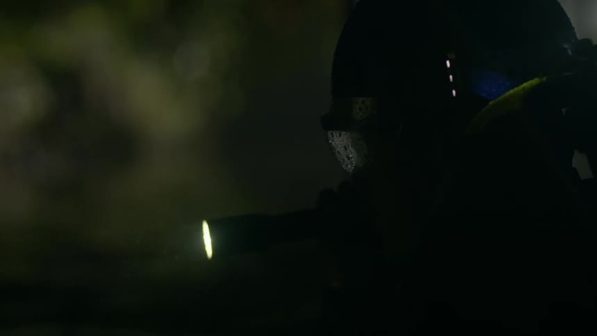 A man searches in the rain with a flashlight