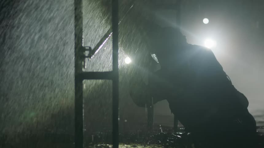 An emergency worker searches with a flashlight during a flood and downpour