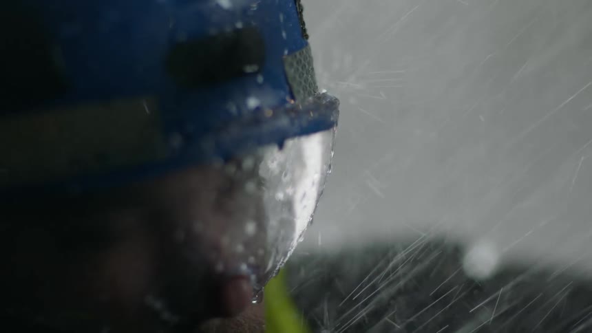 A worker is outside in a rain storm