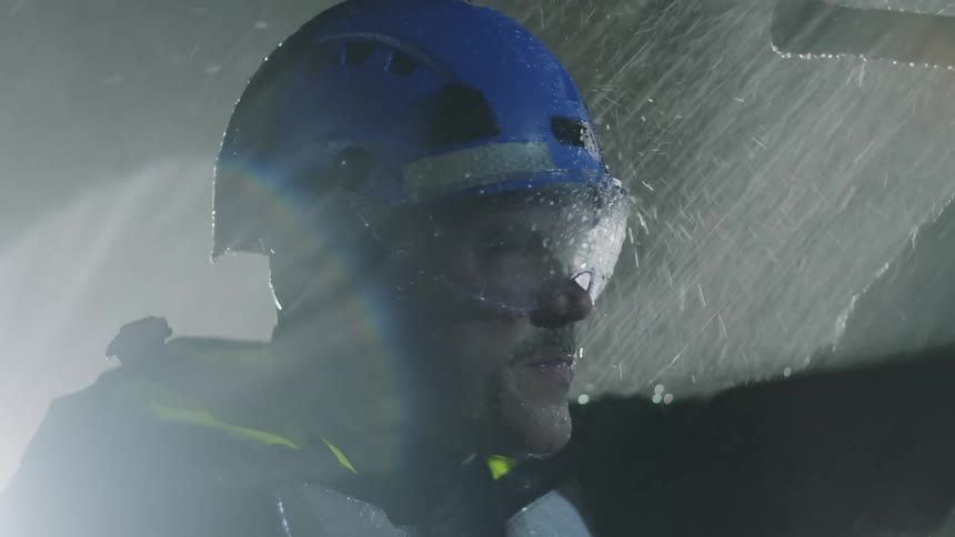 Man standing outside in a downpour of rain at night searching with a flashlight