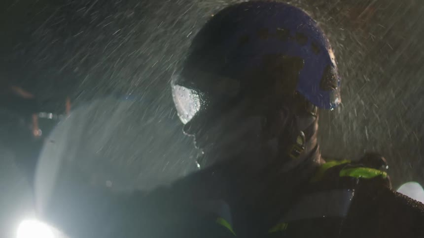 A man is searching with a flashlight during a storm