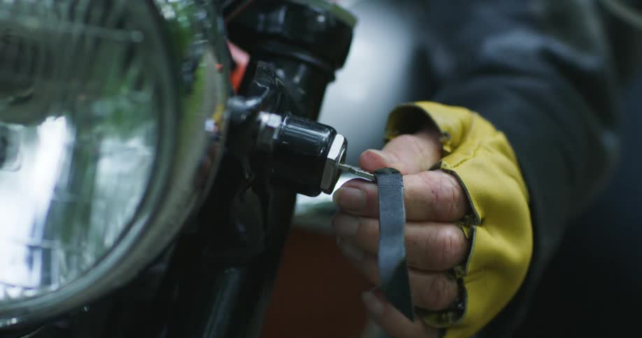Elderly womans hand with a yellow glove starts the motorcycle