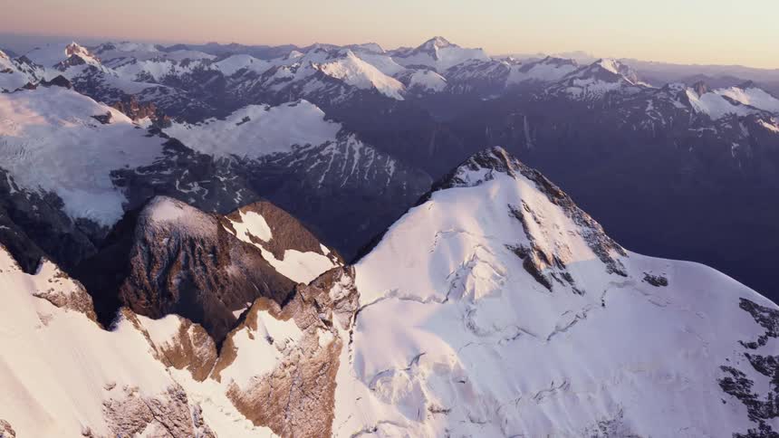 An aerial view of a snowy mountain landscape at dusk