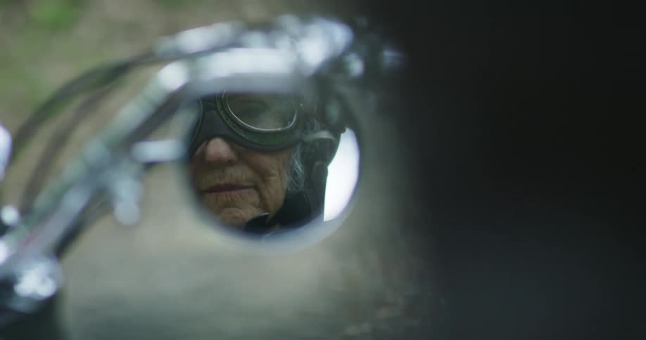 The older person starts the motorcycle