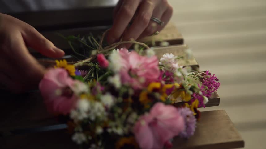 Woman ties string around bouquet of flowers