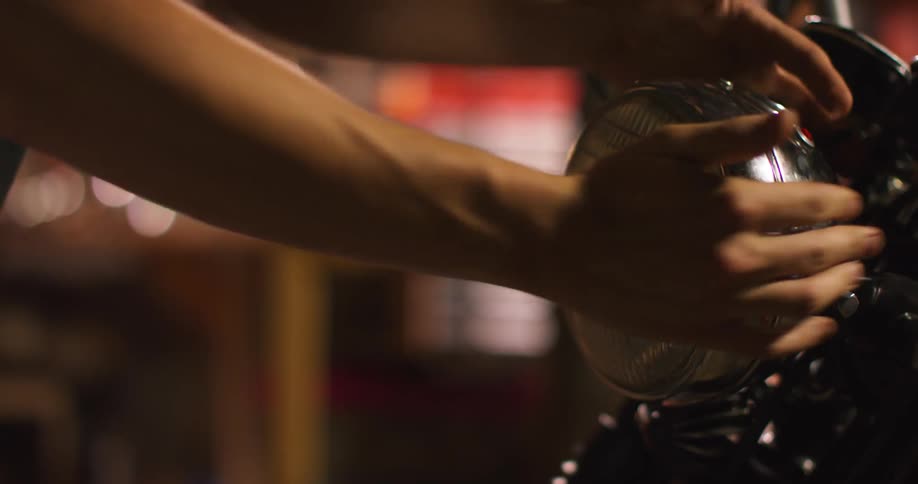 A man puts a cover on a motorcycle headlight and turns the light on