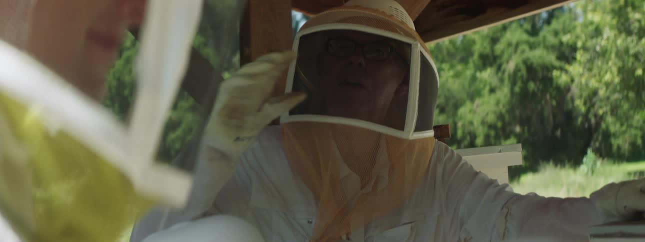 Two bee keepers talk together near a farm