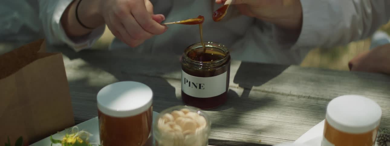 People sitting at a table with jars of honey