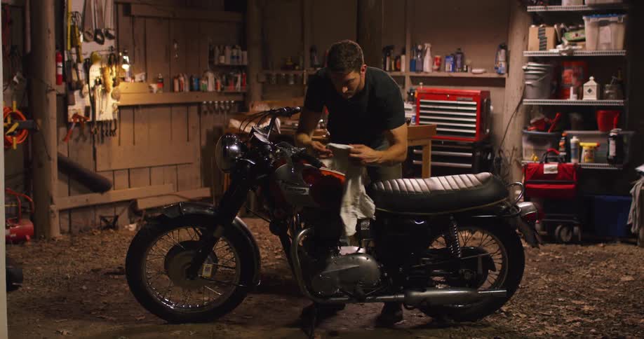 A man wiping down a motorcycle in a shop
