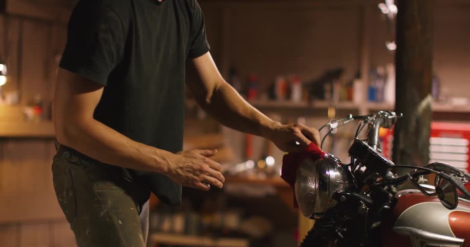 A man uses a towel to shine the chrome of his motorcycle