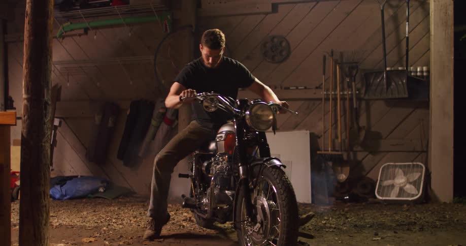 A man is upset after trying to start his broken motorcycle as smoke rises out