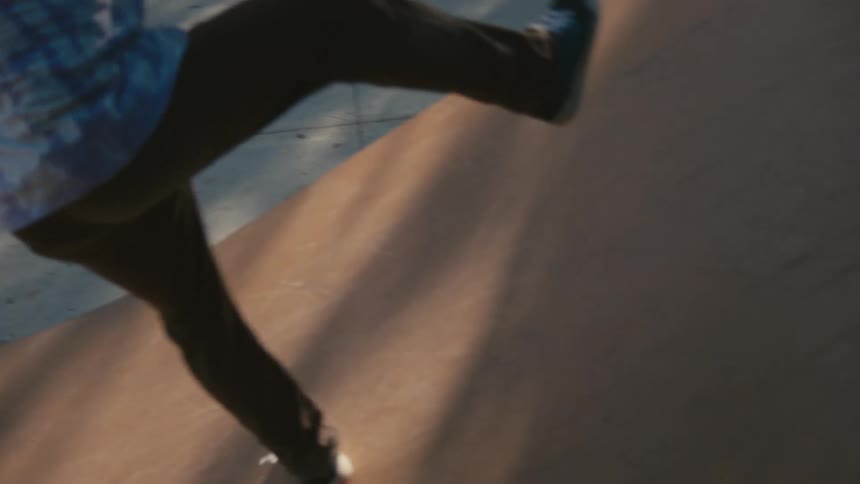 A teenage boy on a ramp in a public park with a skateboard