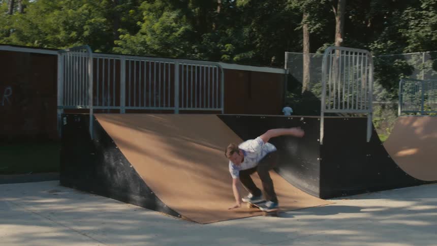 A man skateboards up a plank at a public skate park