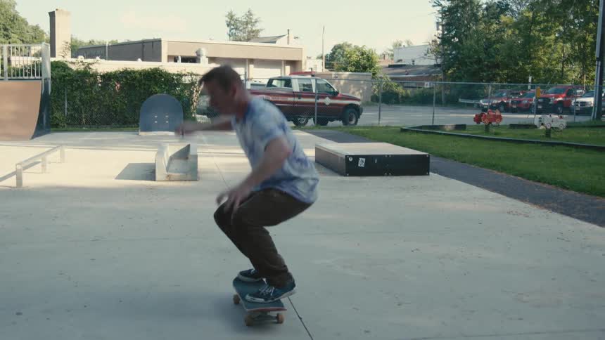 A man doing a kick flip on a skateboard at a skate park
