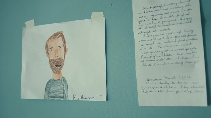 Drawing and written document taped to wall near desk lamp