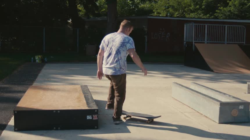 A man kicks his skateboard into his hands