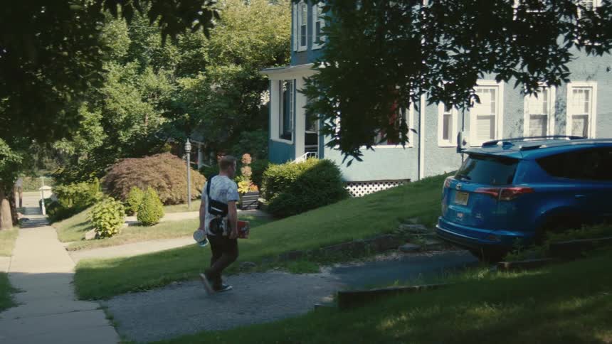 A man walks on the sidewalk towards his driveway