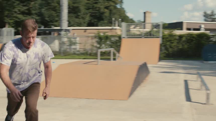 Male skating around in a skatepark at midday